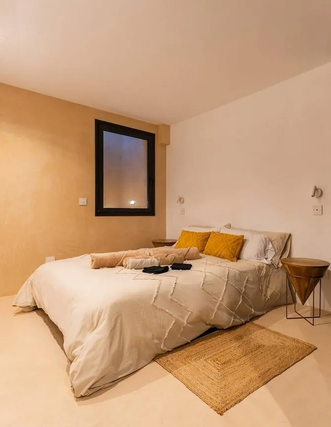 Dormitorio con pared en Estukum y cojines mostaza