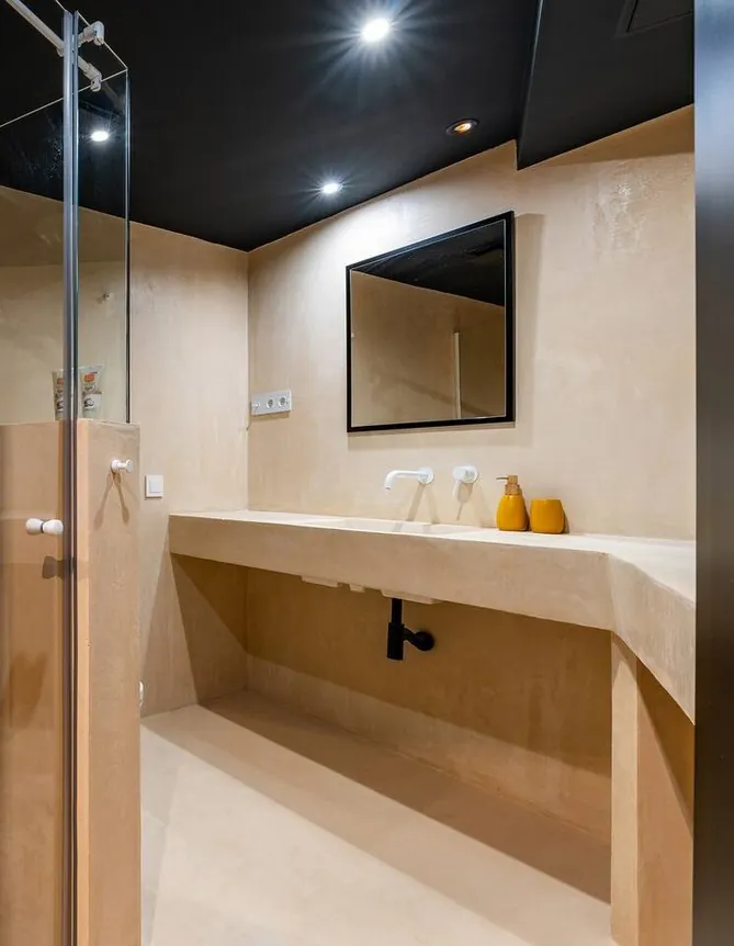 Baño con encimera y pared corrida en Estukum
