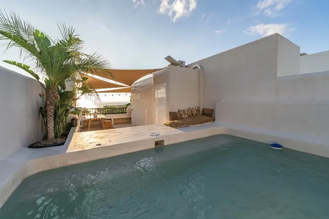 Patio con piscina, palmera y muros en Estukum blanco